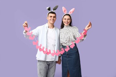 Paskalya çelengi ve leylak arka planda tavşan kulaklı mutlu genç çift.