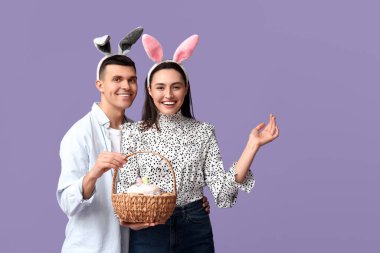 Paskalya sepeti ve leylak arka planda tavşan kulaklı mutlu genç çift.