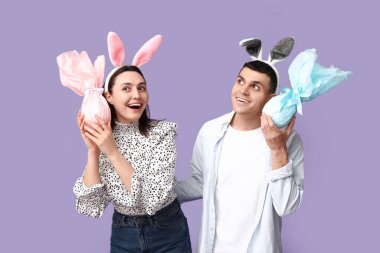 Paskalya hediyeleri ve leylak arka planda tavşan kulaklı mutlu genç çift.