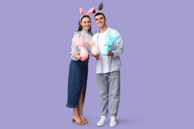 Paskalya hediyeleri ve leylak arka planda tavşan kulaklı mutlu genç çift.