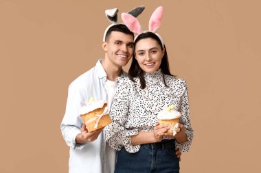 Paskalya pastası ve bej arka planda tavşan kulaklı mutlu genç çift
