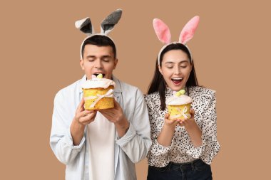 Paskalya pastası ve bej arka planda tavşan kulaklı mutlu genç çift