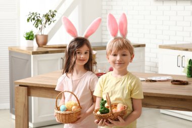 Evde paskalya yumurtası dolu sepetleri olan tavşan kulaklı şirin çocuklar.