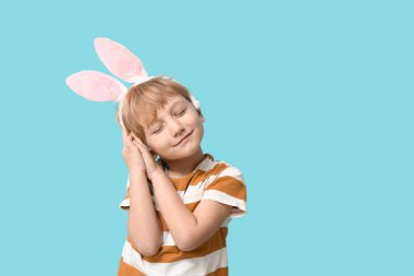 Mavi arka planda tavşan kulaklı rüya gören küçük çocuk.