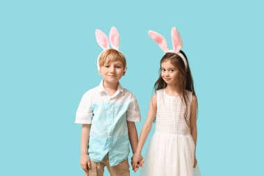 Tavşan kulaklı şirin çocuklar mavi arka planda el ele tutuşuyorlar.