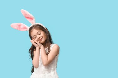 Mavi arka planda tavşan kulaklı küçük bir kız görüyorum.
