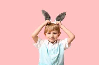 Pembe arka planda tavşan kulaklı şirin bir çocuk.