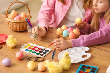 Sevimli küçük kız ve annesi mutfakta paskalya yumurtası boyuyor, yakın plan.