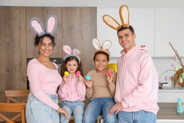 Mutfakta tavşan kulaklı ve paskalya yumurtalı mutlu bir aile.