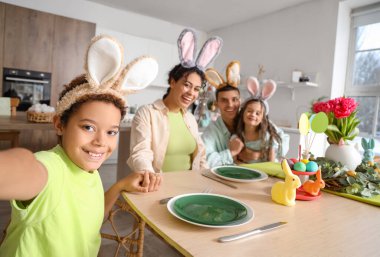 Mutlu bir aile Paskalya günü mutfakta yemek masasında oturuyor.