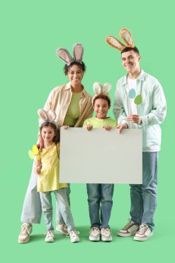 Yeşil arka planda boş posteri olan tavşan kulaklı mutlu bir aile. Paskalya kutlaması