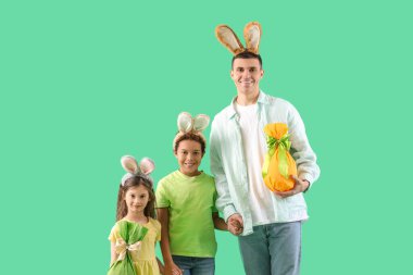 Yeşil arka planda Paskalya hediyesi yumurtaları olan tavşan kulaklı mutlu bir aile.