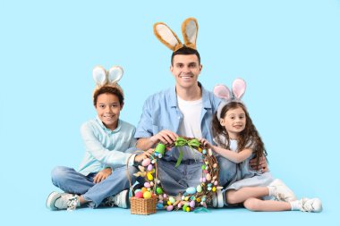 Mutlu baba ve küçük çocukları mavi arka planda oturuyorlar.