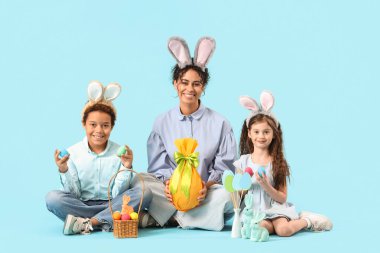 Anneleri ve paskalya yumurtaları mavi arka planda oturan küçük çocuklar.