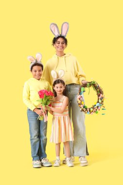 Paskalya çelengi ve sarı arka planda laleleri olan mutlu bir aile.