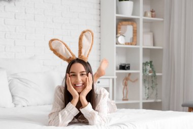 Yatak odasında yatan tavşan kulaklı genç bir kadın. Paskalya kutlaması