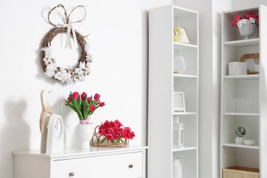 Paskalya için dekore edilmiş oturma odasının içinde çelenk ve klozette laleler var.