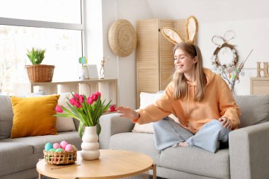 Evde laleleri olan tavşan kulaklı genç bir kadın. Paskalya kutlaması