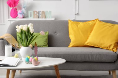 Oturma odasındaki masada vazo, mum ve paskalya yumurtası.