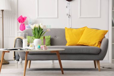 Oturma odasındaki masada vazo, mum ve paskalya yumurtası.