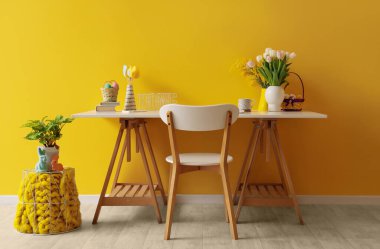 Ofiste sarı duvarın yanında Paskalya yumurtası ve çiçekli bir işyeri.