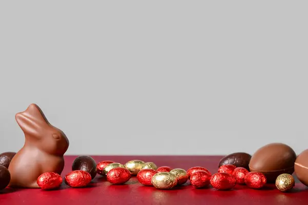 Coelho Chocolate Ovos Páscoa Mesa Vermelha Contra Fundo Cinza — Fotografia de Stock