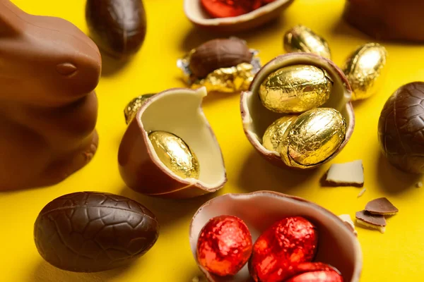 Sarı arka planda çikolatalı Paskalya yumurtası ve tavşan.