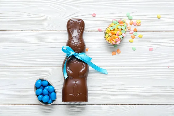 Beyaz ahşap arka planda çikolata, şeker ve tavşanlı Paskalya yumurtaları.