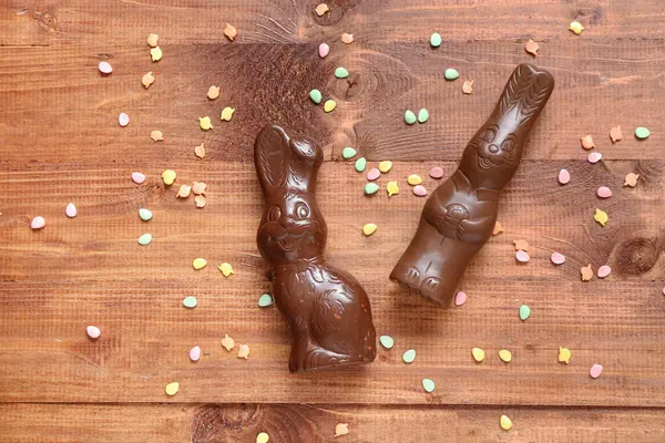 Çikolatalı Paskalya tavşanları ve ahşap zemine serpiştirilmiş çikolata.