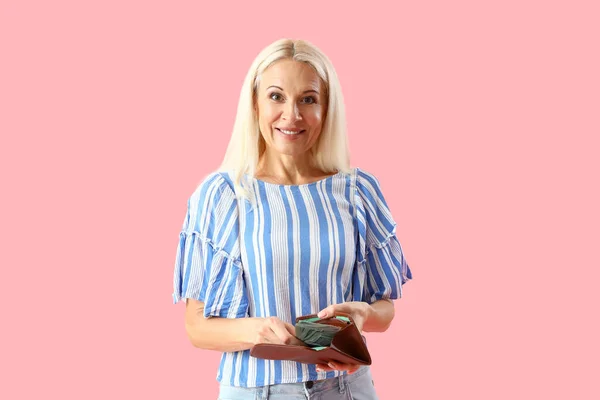Mature woman with wallet on pink background