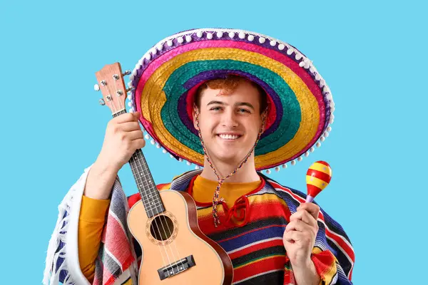Sombrero 'lu genç Meksikalı bir adamın portresi, mavi arka planda gitar ve maraca.