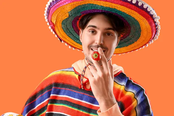 Turuncu arka planda kırmızı biberli genç Meksikalı adam.