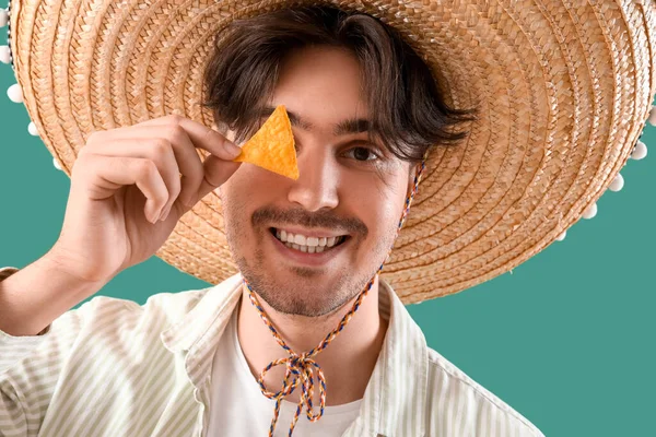 Yeşil arka planda cipsleri olan genç Meksikalı adam.