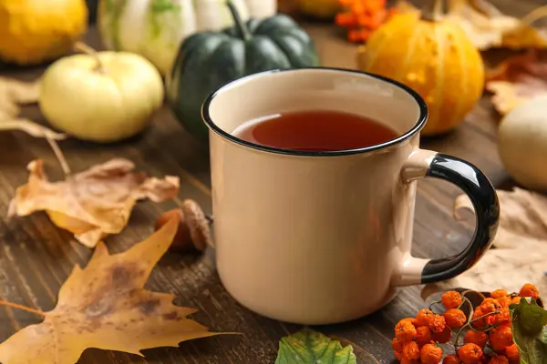 Kabaklı kompozisyon, bir fincan çay ve kahverengi ahşap arka planda sonbahar yaprakları