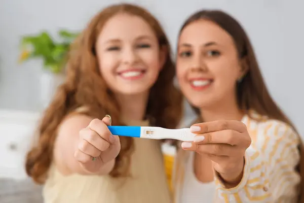 Happy young lesbian couple with pregnancy test at home, closeup