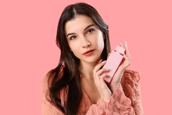 ピンクの背景に香水を持つ若い女性 クローズアップ — ストック写真