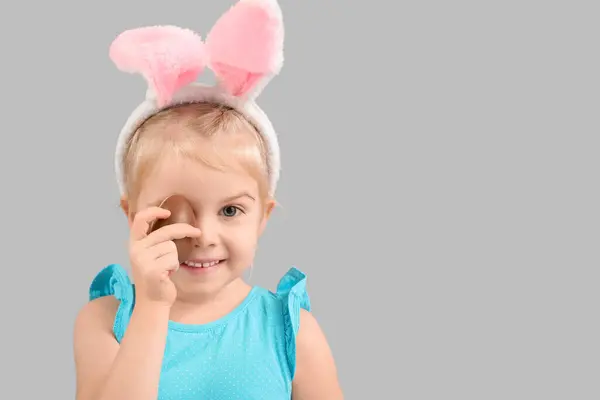 在兔子耳朵里的快乐小女孩 有着灰色背景的巧克力蛋 复活节庆祝活动 — 图库照片
