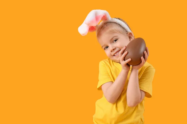 在兔子耳朵里快乐的小女孩 背景是黄色的巧克力蛋 复活节庆祝活动 — 图库照片