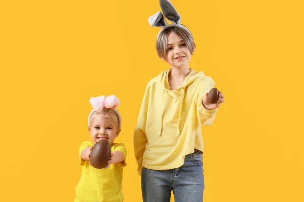 在兔子耳朵里可爱的小孩 背景是黄色的巧克力蛋 复活节庆祝活动 — 图库照片
