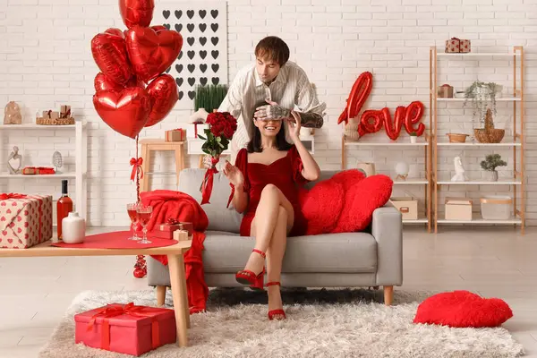 Genç adam sevgilisini sevgililer gününde evde karşılıyor.