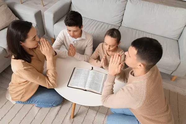 Aile evde İncil 'le dua ediyor.