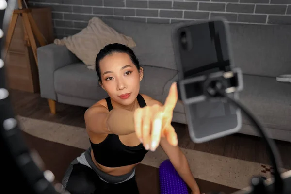Female Asian sports blogger with mobile phone recording video at home