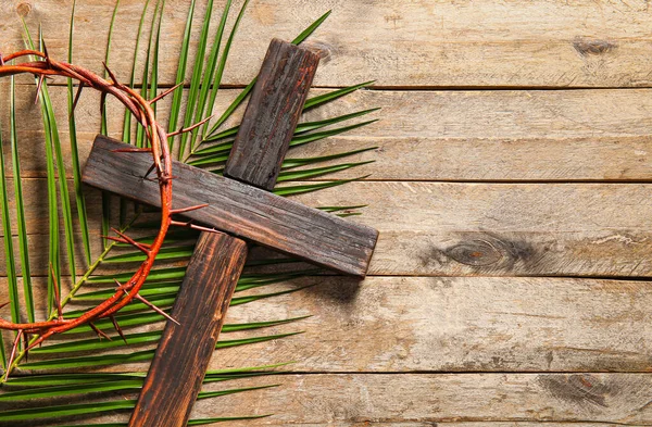 Palmiye yaprağı ve dikenli taç ile ahşap zemin üzerinde çapraz