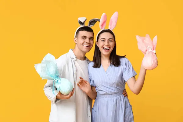 Šťastný Mladý Pár Velikonoční Zajíček Uši Dárky Žlutém Pozadí — Stock fotografie