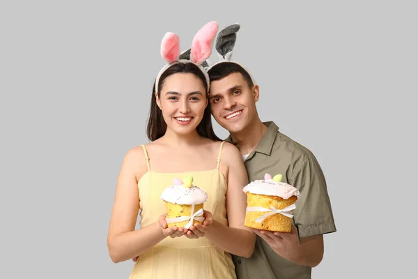 Šťastný Mladý Pár Velikonoční Dorty Králičí Uši Šedém Pozadí — Stock fotografie
