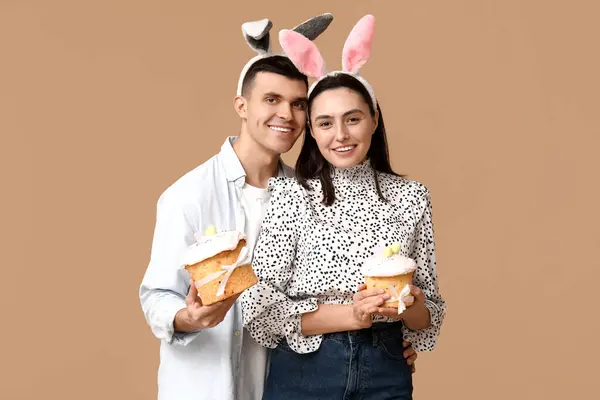 Paskalya pastası ve bej arka planda tavşan kulaklı mutlu genç çift