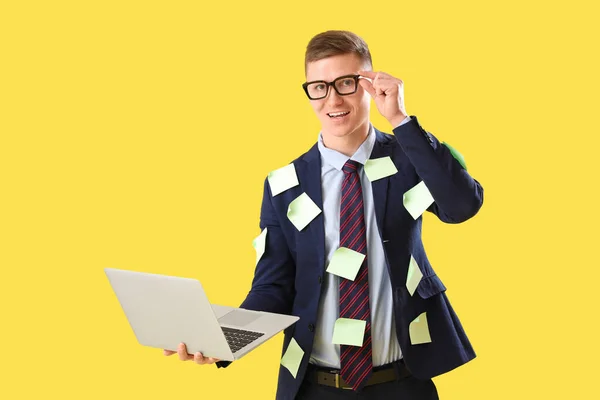 Funny businessman with sticky notes and laptop on yellow background