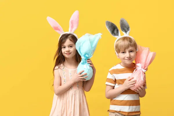 带着黄色背景的复活节彩蛋的兔子耳朵里可爱的小孩 — 图库照片