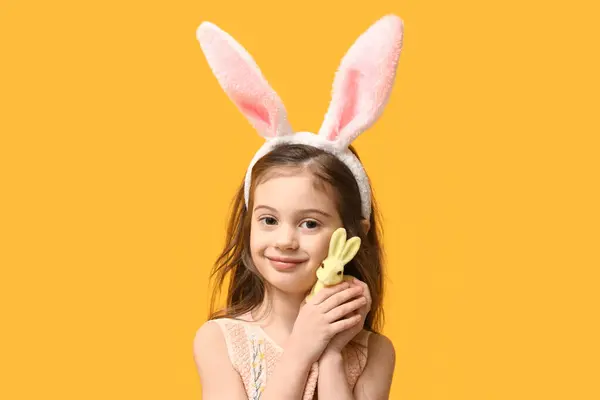 黄色の背景にイースターウサギとバニーの耳にかわいい少女 — ストック写真
