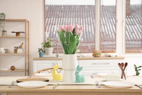 Mutfaktaki yemek masasında vazo, lale ve Paskalya tavşanı.